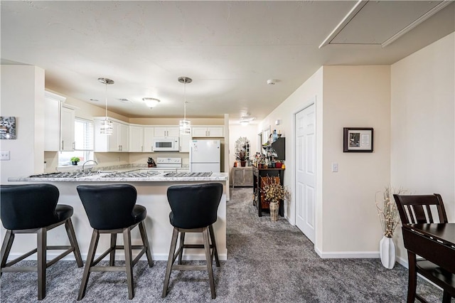 kitchen with dark carpet, white appliances, white cabinets, hanging light fixtures, and kitchen peninsula