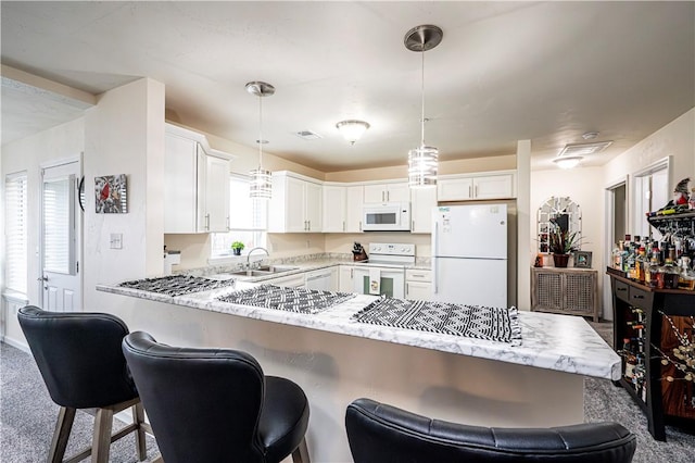 kitchen with kitchen peninsula, decorative light fixtures, white appliances, and white cabinets