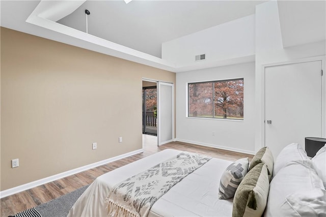 bedroom with light hardwood / wood-style flooring and a towering ceiling