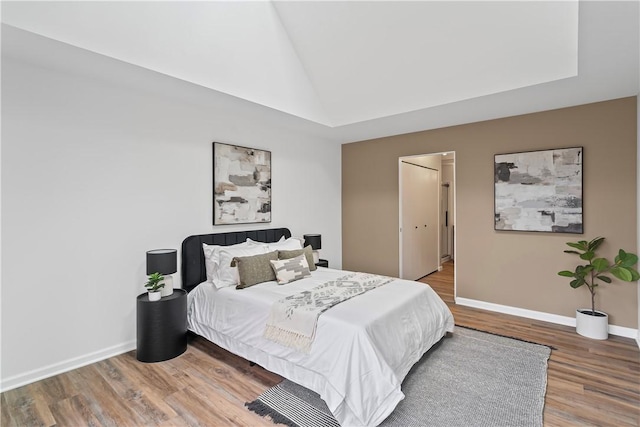 bedroom with wood-type flooring and lofted ceiling