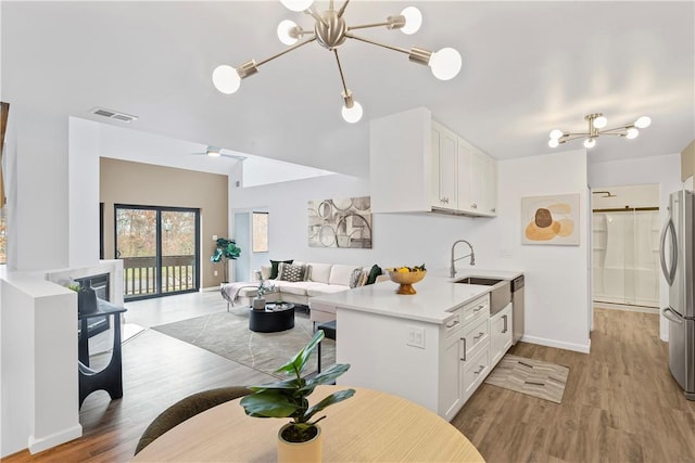 kitchen featuring white cabinets, stainless steel fridge, light hardwood / wood-style floors, and kitchen peninsula