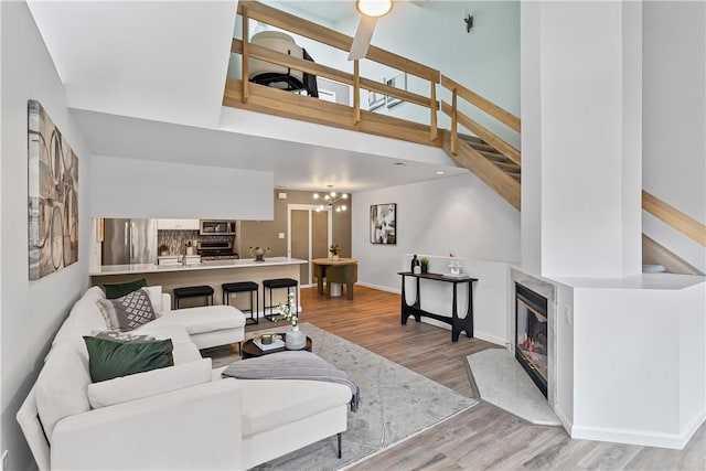 living room with a fireplace, a high ceiling, and light wood-type flooring