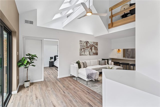 living room featuring light hardwood / wood-style flooring, high vaulted ceiling, and ceiling fan