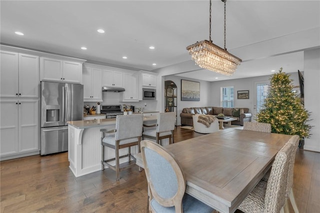 dining area with dark wood-type flooring and an inviting chandelier