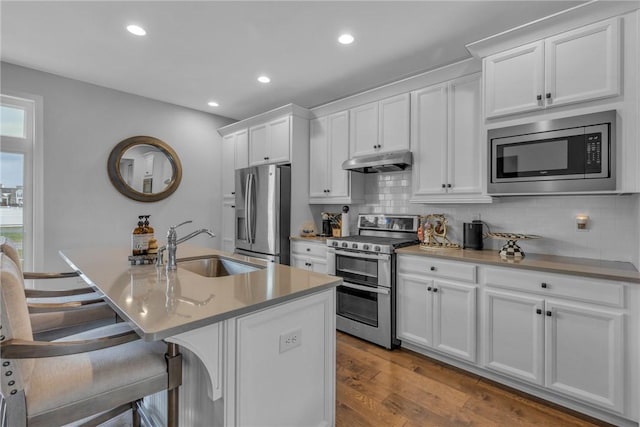 kitchen featuring a kitchen island with sink, sink, light hardwood / wood-style flooring, white cabinetry, and stainless steel appliances