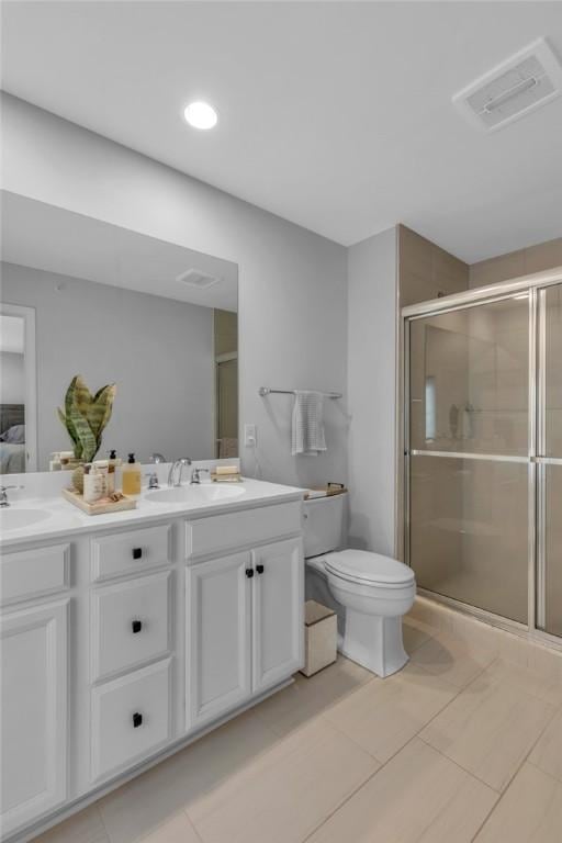 bathroom featuring toilet, vanity, tile patterned floors, and a shower with door