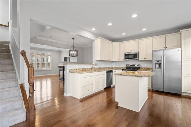 kitchen featuring decorative light fixtures, dark hardwood / wood-style flooring, stainless steel appliances, and ornamental molding