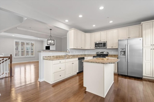 kitchen with kitchen peninsula, hardwood / wood-style floors, stainless steel appliances, and decorative light fixtures