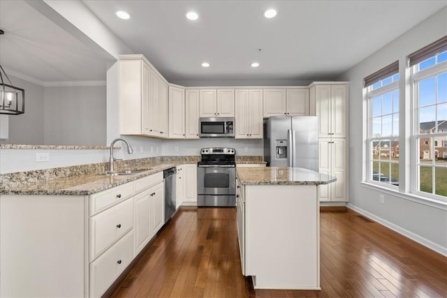 kitchen with a healthy amount of sunlight, white cabinets, hanging light fixtures, and appliances with stainless steel finishes