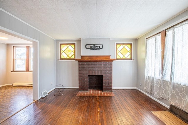 unfurnished living room with a fireplace, a healthy amount of sunlight, and dark hardwood / wood-style floors