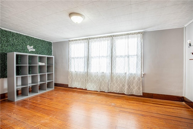 empty room featuring wood-type flooring and ornamental molding