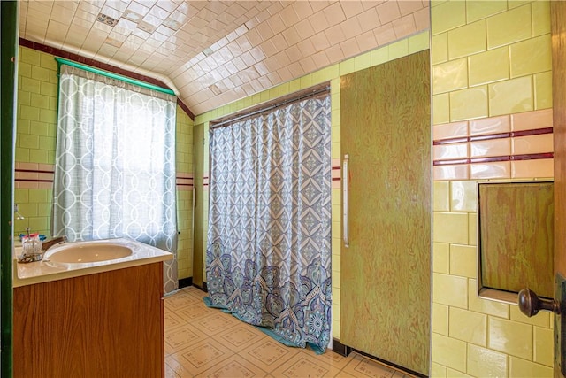 bathroom with tile walls, vanity, lofted ceiling, and a shower with shower curtain