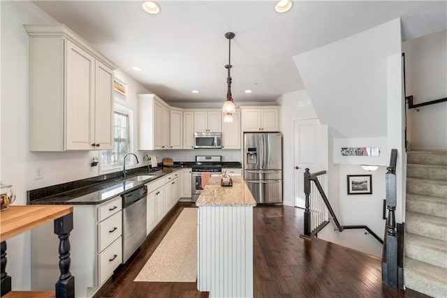 kitchen featuring dark hardwood / wood-style floors, stainless steel appliances, hanging light fixtures, and sink