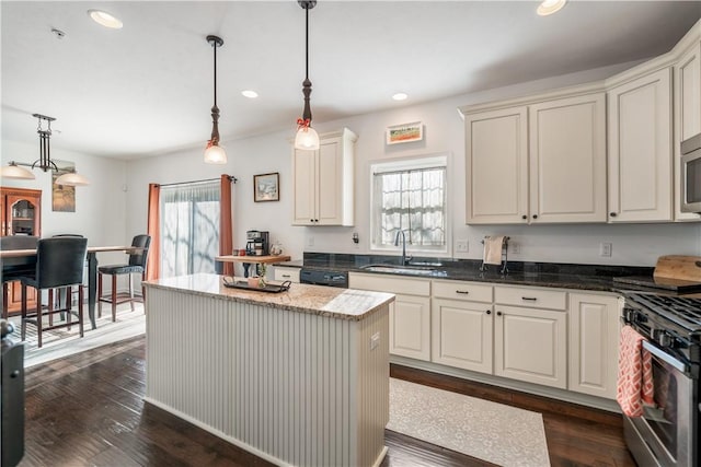 kitchen featuring stainless steel appliances, dark wood-type flooring, sink, a kitchen island, and hanging light fixtures