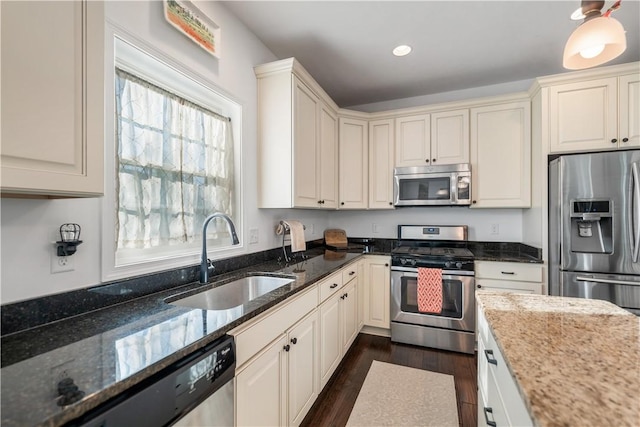 kitchen with dark hardwood / wood-style flooring, dark stone counters, stainless steel appliances, sink, and white cabinetry