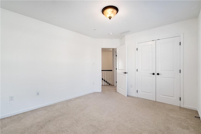 unfurnished bedroom with light carpet and a closet