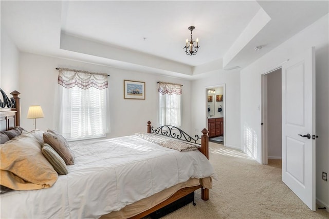 bedroom featuring ensuite bathroom, an inviting chandelier, a tray ceiling, and light colored carpet