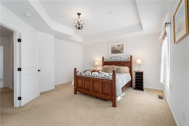 bedroom featuring a raised ceiling, light carpet, and a notable chandelier