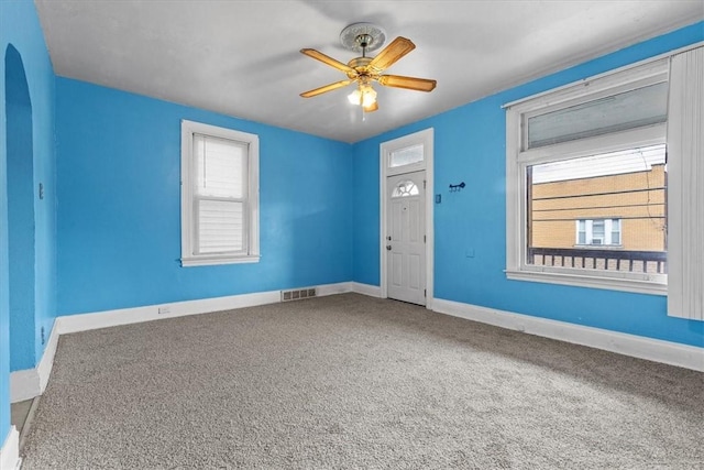 carpeted empty room with a wealth of natural light and ceiling fan