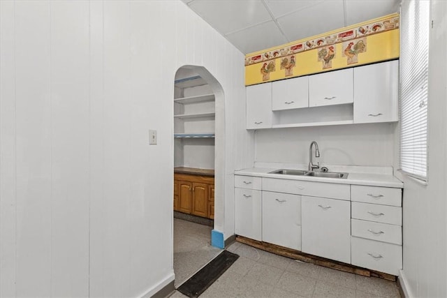 kitchen with white cabinets, sink, and wooden walls