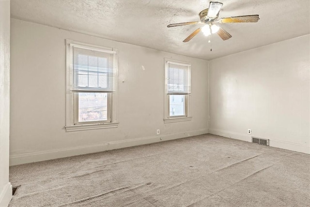 carpeted empty room featuring ceiling fan and a textured ceiling