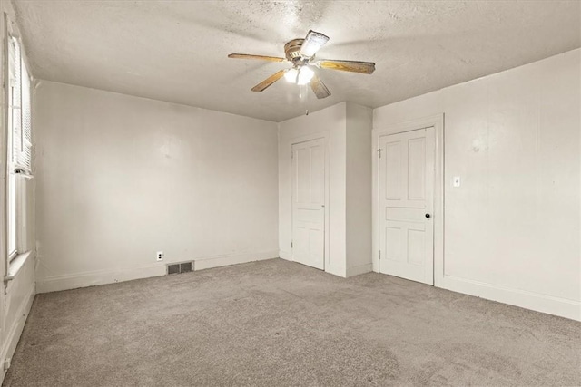 unfurnished bedroom featuring carpet flooring, a textured ceiling, and ceiling fan