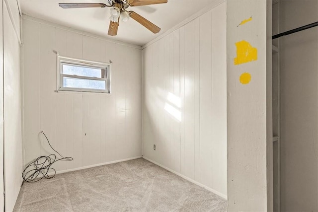 unfurnished room with light colored carpet, ceiling fan, crown molding, and wood walls