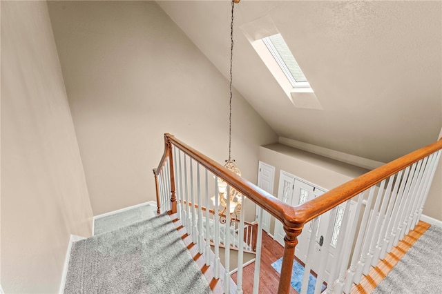 stairway featuring lofted ceiling with skylight and carpet floors