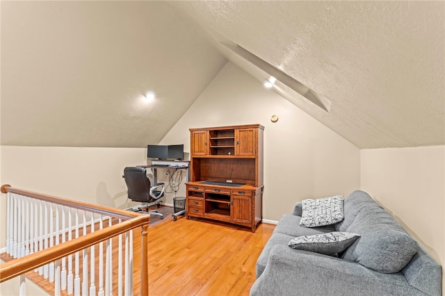 office area featuring lofted ceiling, a textured ceiling, and light wood-type flooring