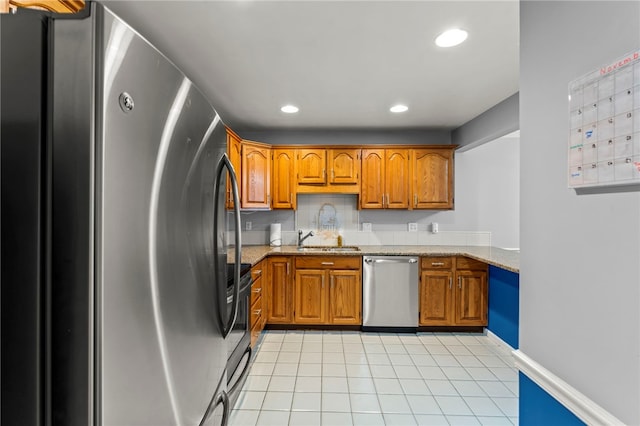 kitchen featuring light stone counters, appliances with stainless steel finishes, sink, and light tile patterned floors