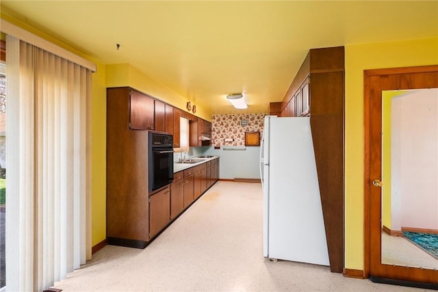 kitchen featuring white fridge, oven, and sink