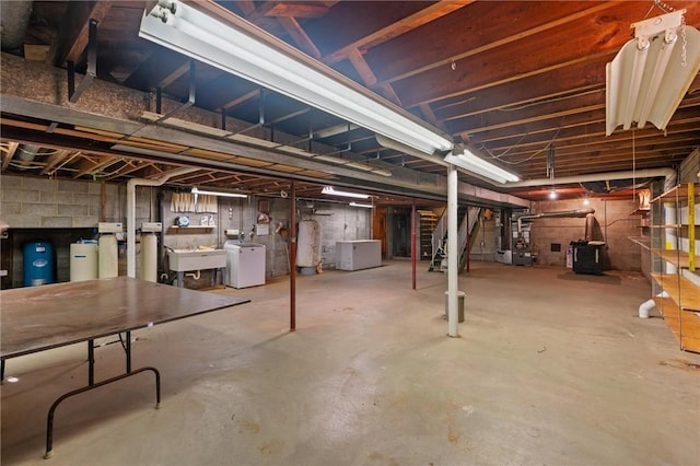 basement featuring separate washer and dryer, gas water heater, and sink