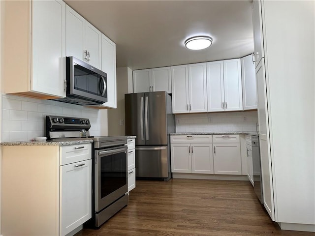 kitchen with tasteful backsplash, white cabinetry, dark wood-type flooring, and stainless steel appliances