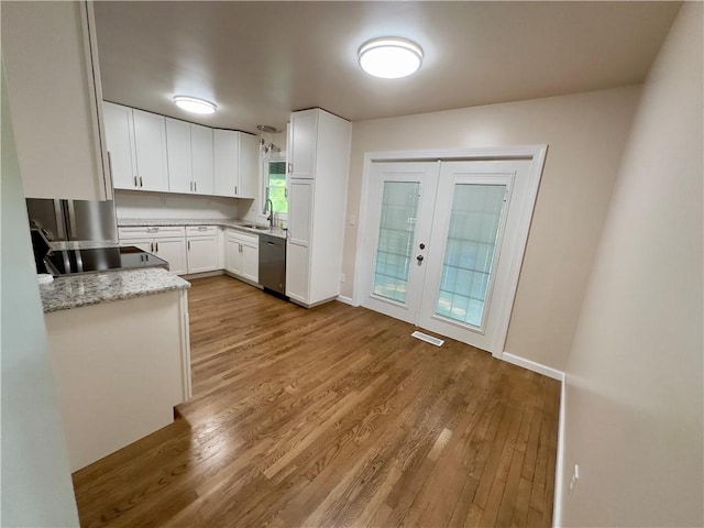 kitchen with light stone countertops, french doors, dishwasher, light hardwood / wood-style floors, and white cabinetry