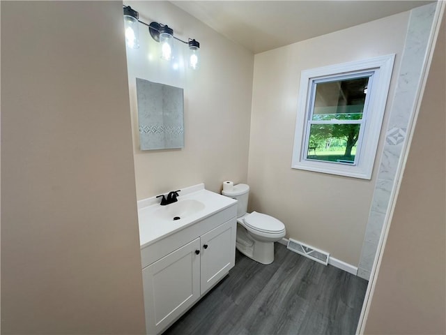 bathroom with wood-type flooring, vanity, and toilet