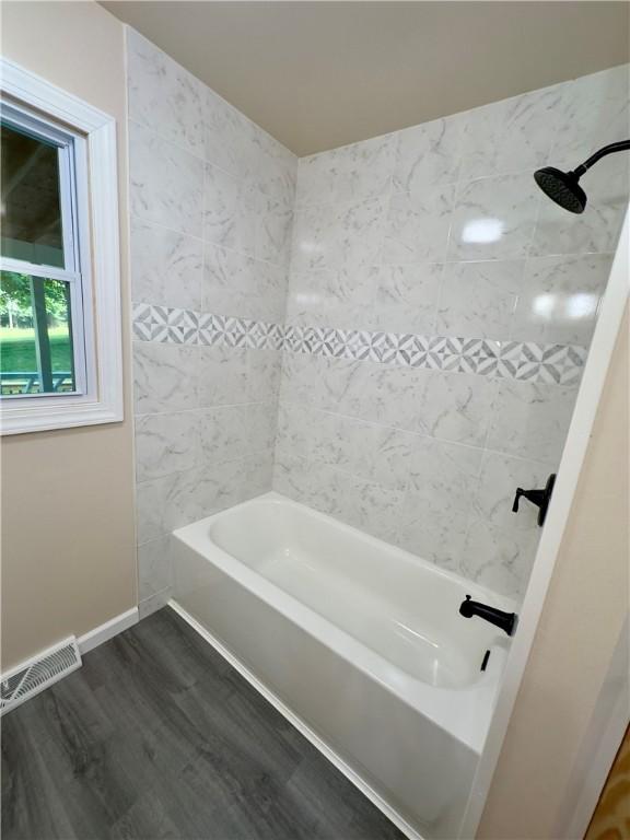 bathroom with hardwood / wood-style floors and tiled shower / bath combo