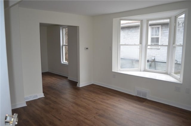 spare room featuring a healthy amount of sunlight and dark hardwood / wood-style floors