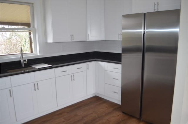 kitchen with white cabinets, sink, dark hardwood / wood-style floors, decorative backsplash, and stainless steel refrigerator