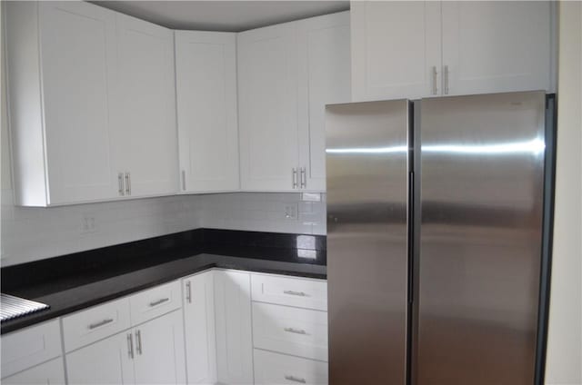 kitchen featuring stainless steel fridge, tasteful backsplash, and white cabinetry