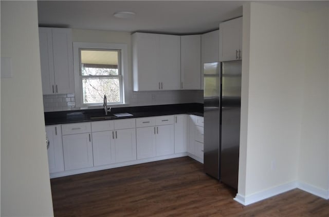 kitchen with decorative backsplash, stainless steel fridge, sink, and white cabinets