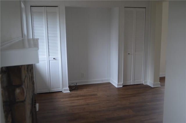 unfurnished bedroom with multiple closets and dark hardwood / wood-style floors