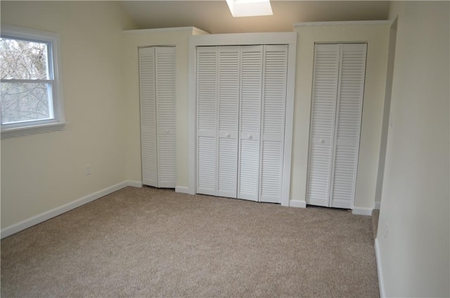 unfurnished bedroom with lofted ceiling, light colored carpet, and multiple closets