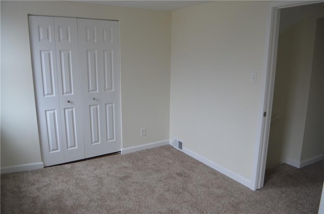 unfurnished bedroom featuring light colored carpet and a closet