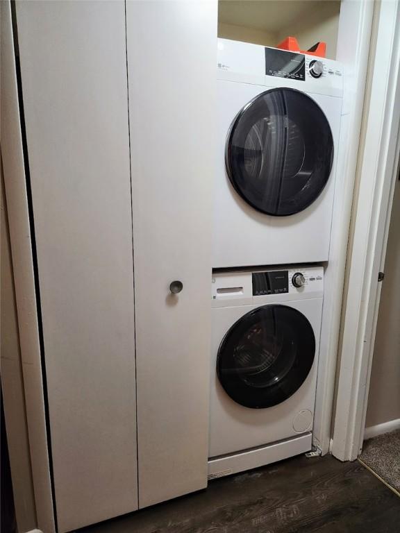 clothes washing area featuring dark hardwood / wood-style flooring and stacked washer / drying machine