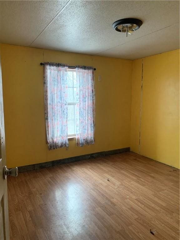 unfurnished room with wood-type flooring and a textured ceiling