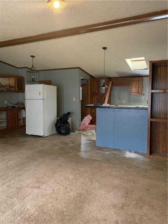 kitchen with a skylight, a textured ceiling, crown molding, white refrigerator, and decorative light fixtures