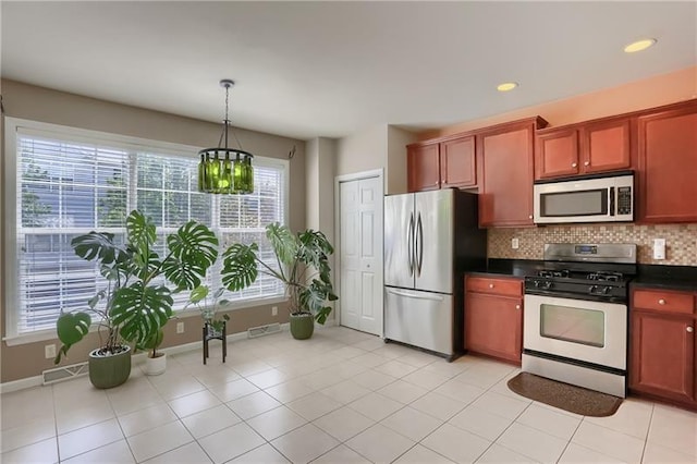 kitchen featuring decorative backsplash, appliances with stainless steel finishes, hanging light fixtures, and a healthy amount of sunlight