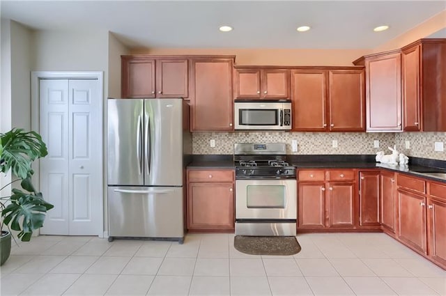 kitchen with appliances with stainless steel finishes, backsplash, light tile patterned floors, and sink