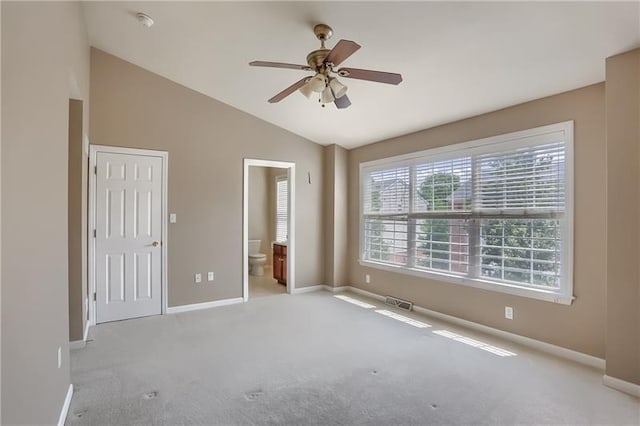 unfurnished bedroom featuring connected bathroom, ceiling fan, light colored carpet, and vaulted ceiling