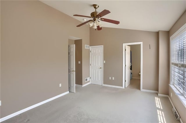 unfurnished bedroom featuring light carpet, ensuite bathroom, vaulted ceiling, ceiling fan, and a closet